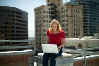 密歇根州立大学丹佛 student studying with the 丹佛 skyline behind her